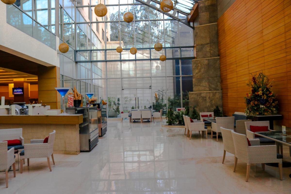 a dining room with tables and chairs in a building at Radisson Blu Hotel, Greater Noida in Greater Noida