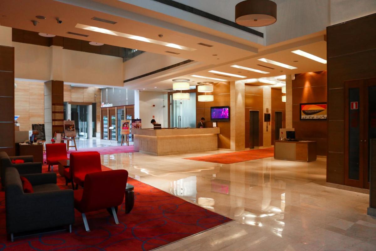 a lobby with red chairs and a waiting room at Radisson Blu Hotel, Greater Noida in Greater Noida