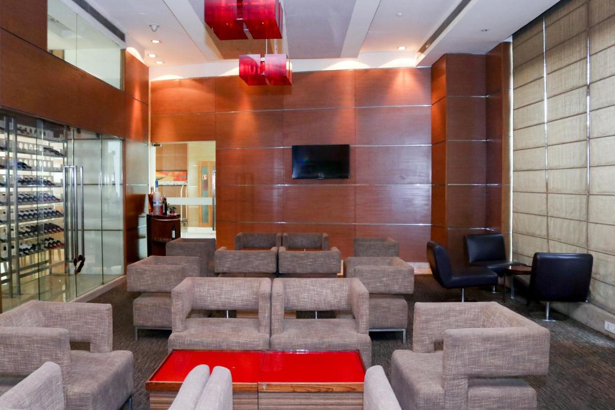 a waiting room with chairs and a tv on a wall at Radisson Blu Hotel, Greater Noida in Greater Noida