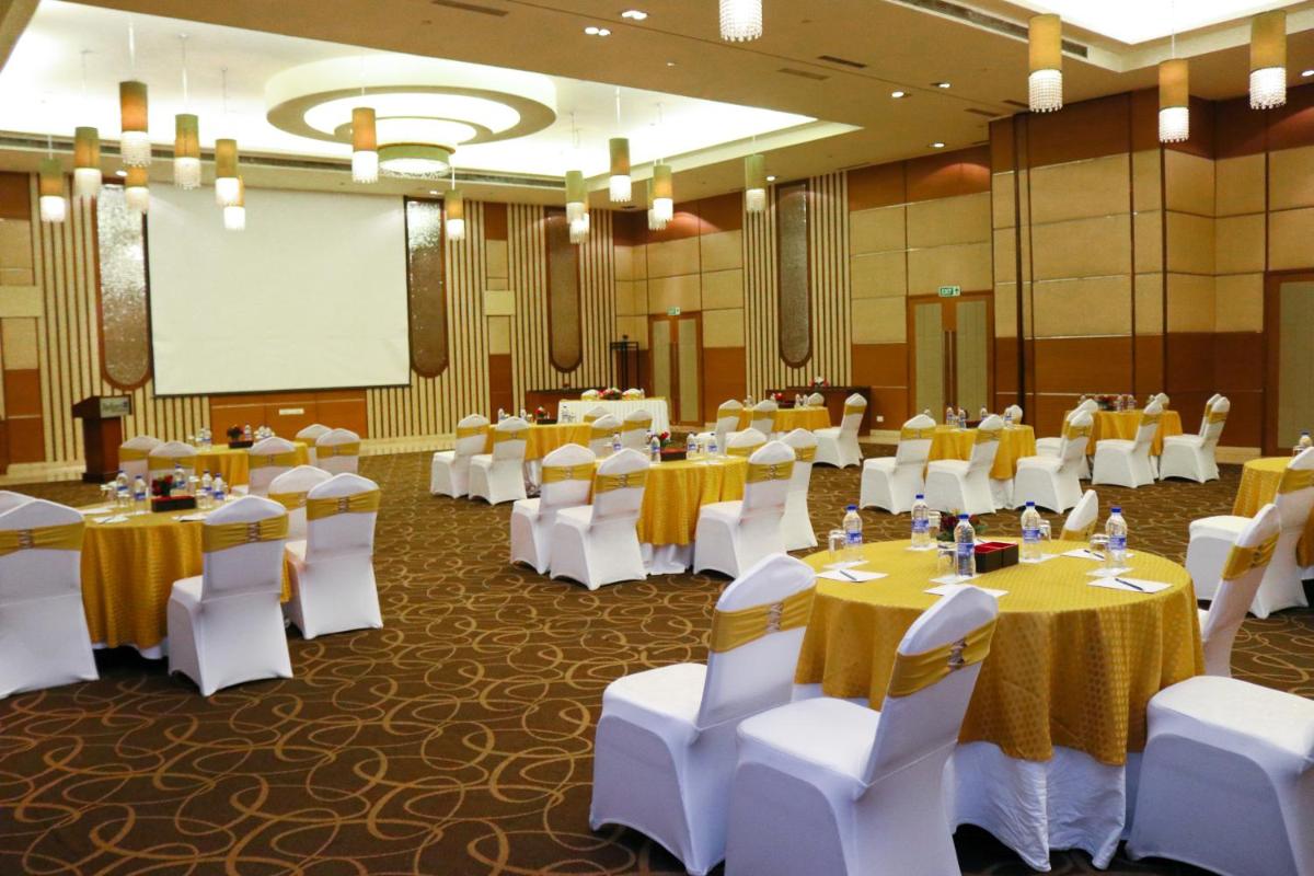 a banquet hall with tables and white chairs and a screen at Radisson Blu Hotel, Greater Noida in Greater Noida