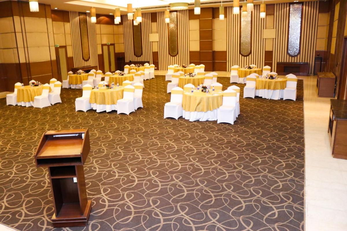 a banquet hall with white tables and a podium at Radisson Blu Hotel, Greater Noida in Greater Noida