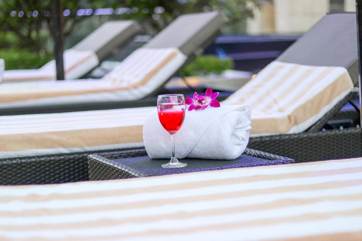 a glass of wine sitting on a table near a pool at Radisson Blu Hotel, Greater Noida in Greater Noida