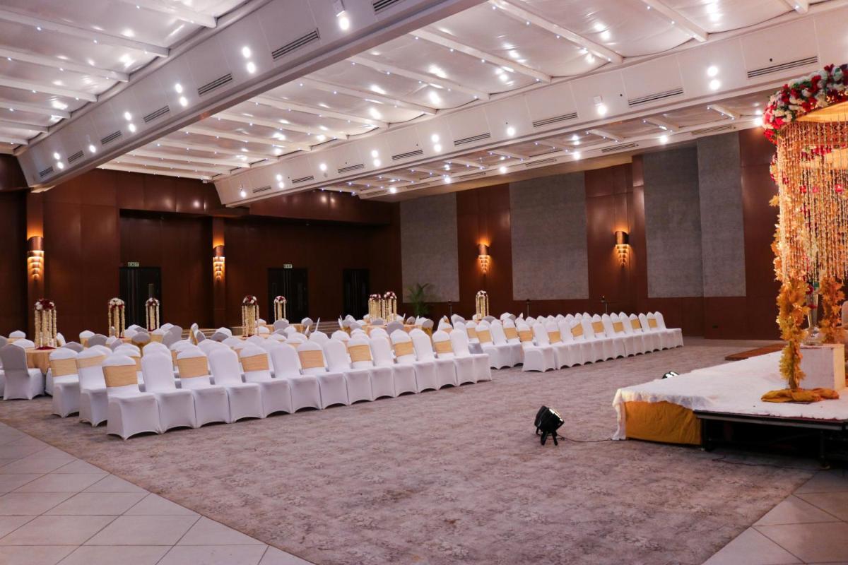 a banquet hall with white chairs and a cat standing in the middle at Radisson Blu Hotel, Greater Noida in Greater Noida