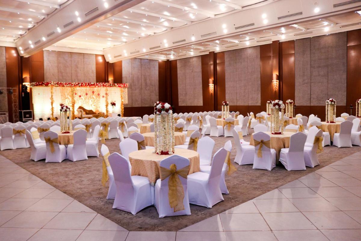 a banquet hall with white tables and chairs and a stage at Radisson Blu Hotel, Greater Noida in Greater Noida