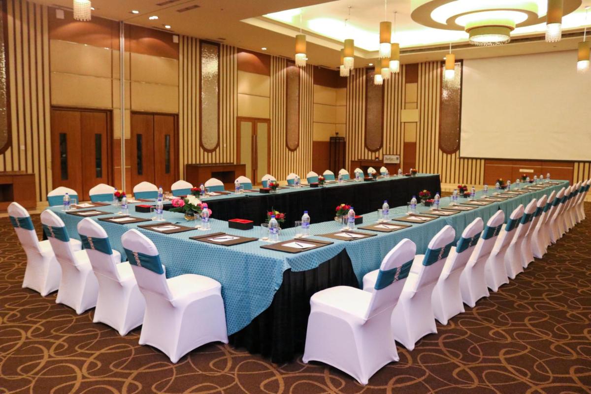 a long table in a room with white chairs at Radisson Blu Hotel, Greater Noida in Greater Noida