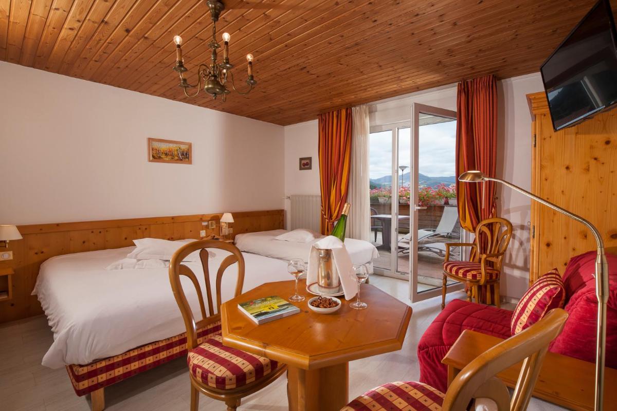 une chambre d'hôtel avec un lit, une table et des chaises dans l'établissement Logis Hostellerie Motel Au Bois Le Sire, à Orbey