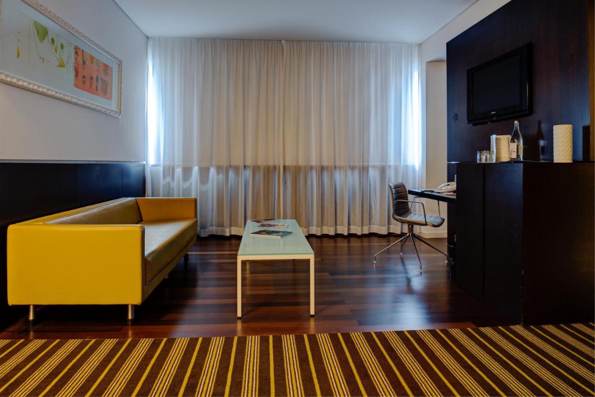 uma sala de estar com um sofá amarelo e uma mesa em VIP Grand Lisboa Hotel & Spa em Lisboa