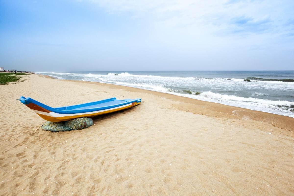 a boat sitting on a beach next to the ocean at Novotel Chennai Chamiers Road in Chennai