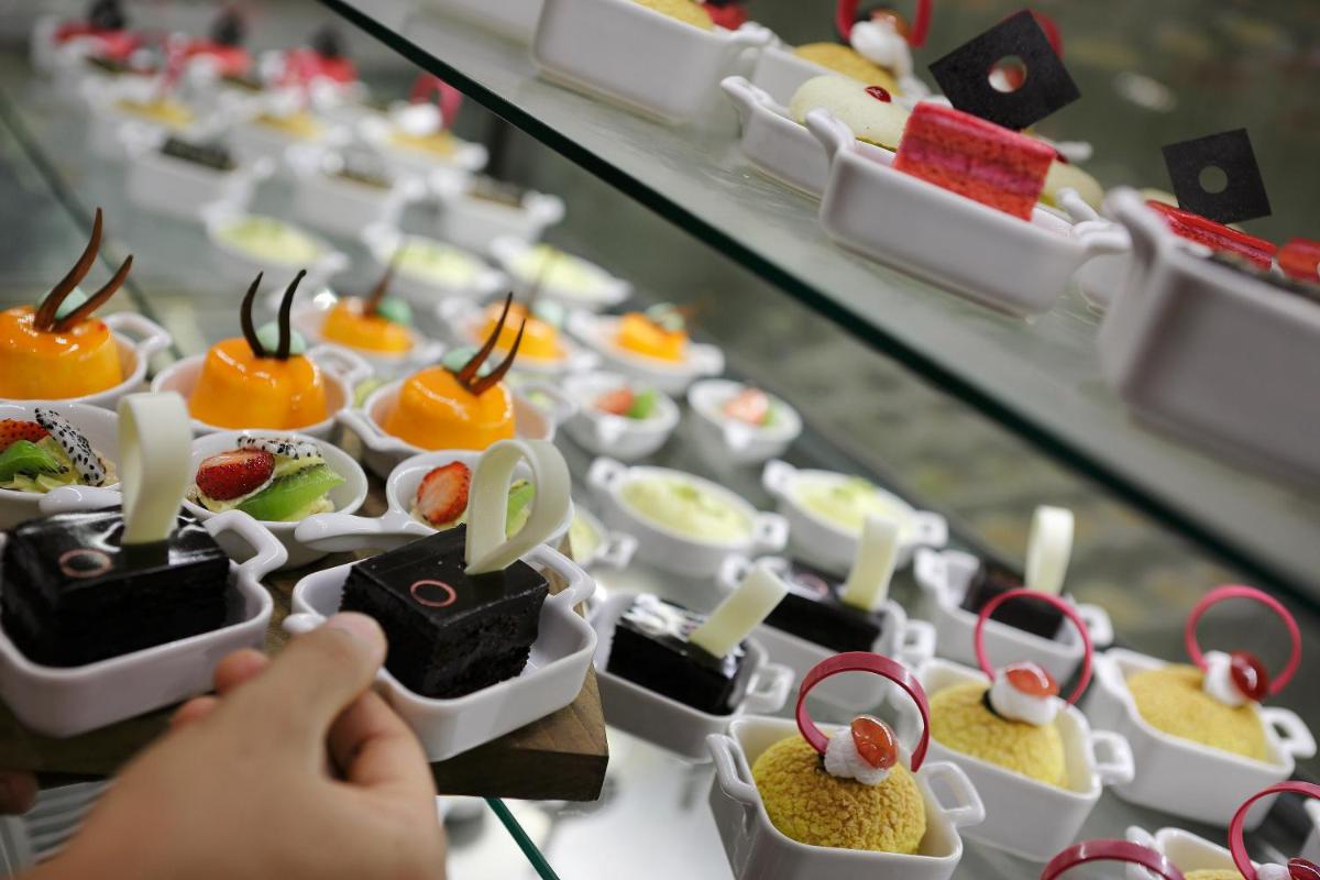 a person taking a picture of a variety of desserts at Novotel Chennai Chamiers Road in Chennai