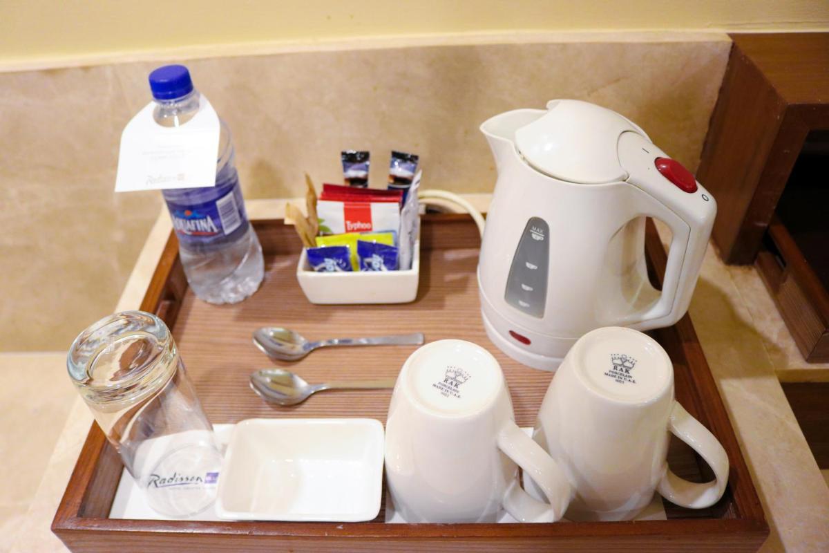 a tray with a tea kettle and spoons and a bottle of water at Radisson Blu Hotel, Greater Noida in Greater Noida