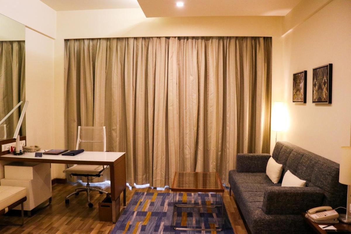 a living room with a couch and a table and a desk at Radisson Blu Hotel, Greater Noida in Greater Noida