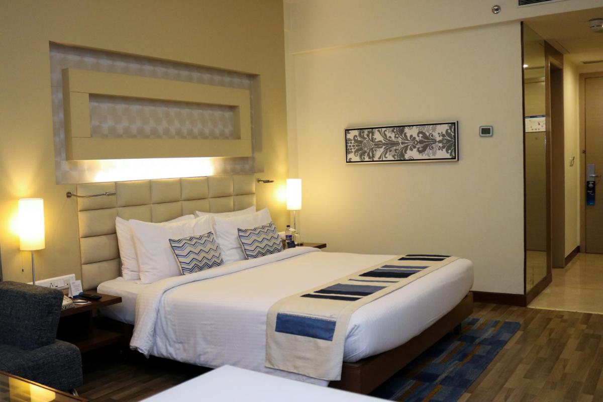 a hotel room with a large bed and a chair at Radisson Blu Hotel, Greater Noida in Greater Noida