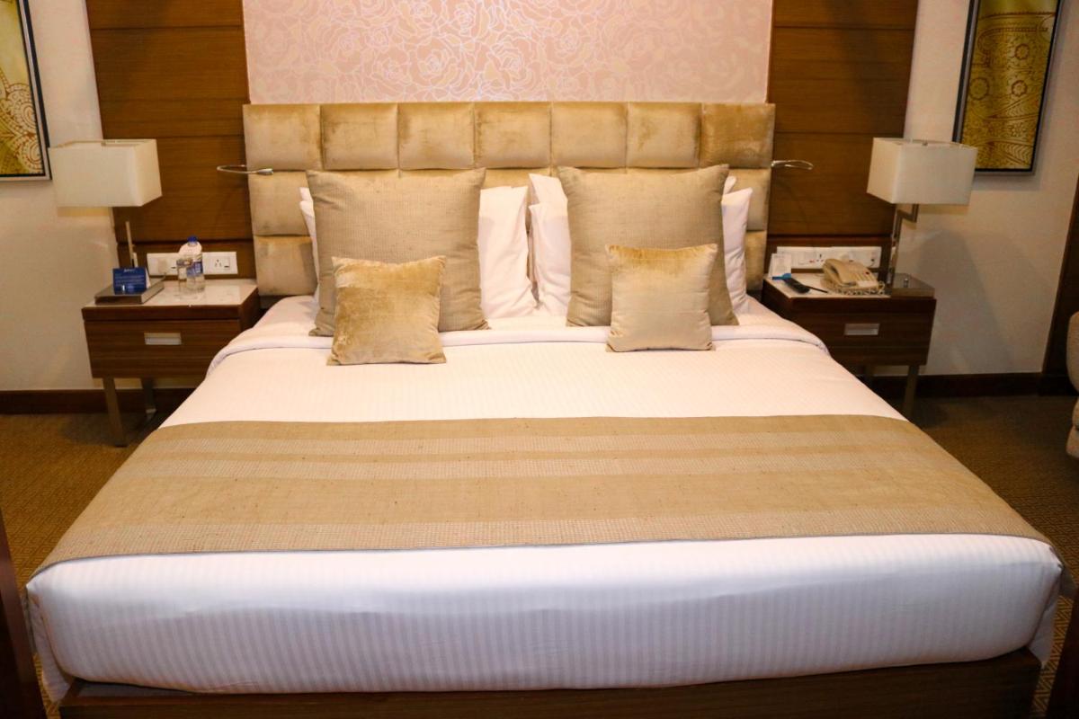 a large bed in a hotel room with two tables at Radisson Blu Hotel, Greater Noida in Greater Noida