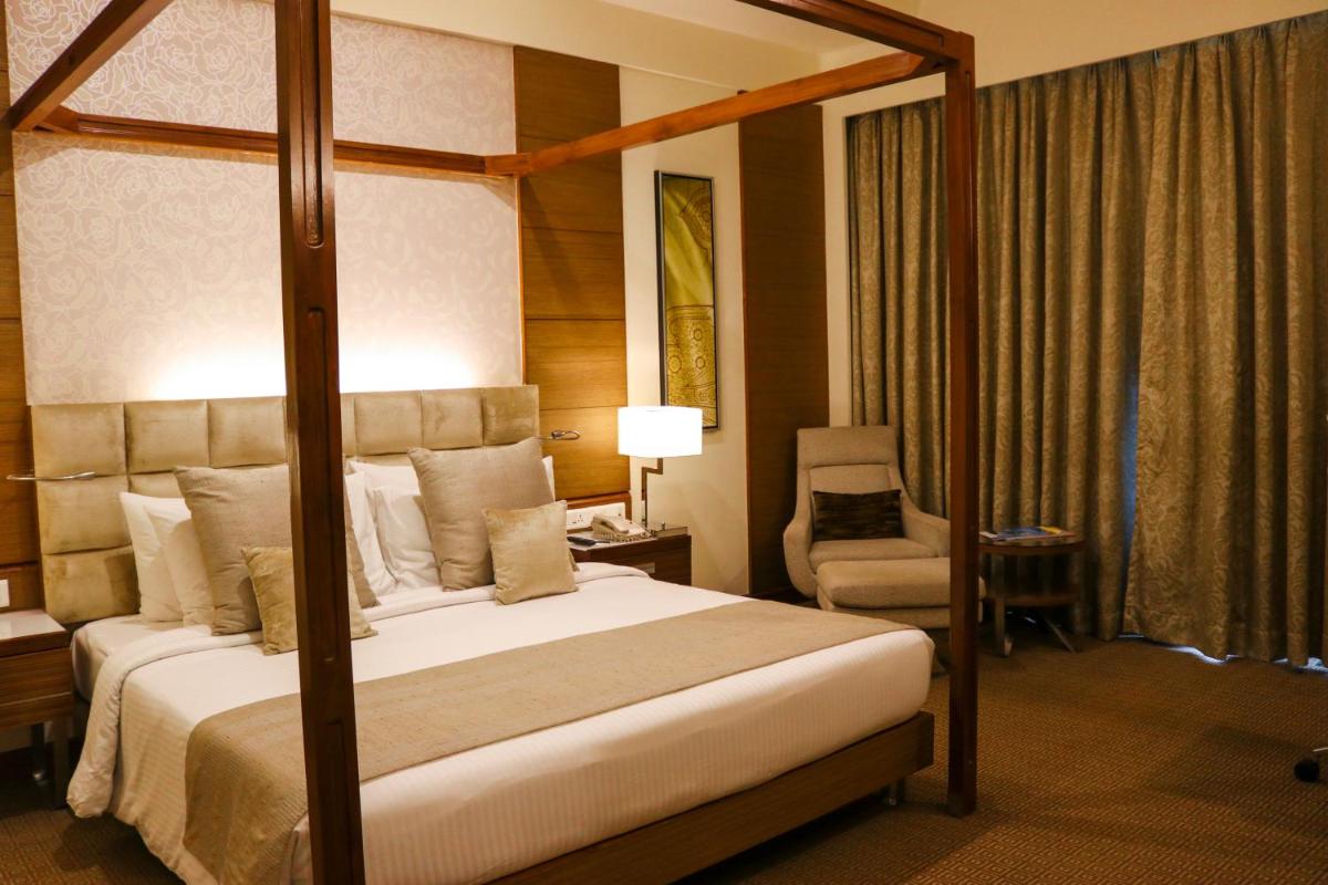 a bedroom with a canopy bed and a chair at Radisson Blu Hotel, Greater Noida in Greater Noida