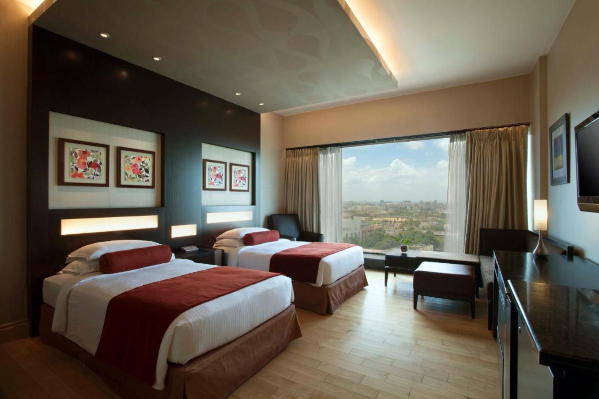 a hotel room with two beds and a desk at The Oterra in Bengaluru a hotel room with two beds and a desk at The Oterra in Bengaluru