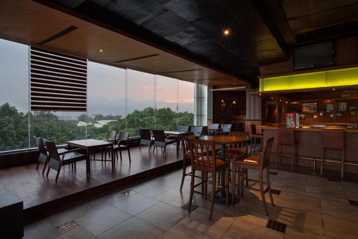 a restaurant with tables and chairs and large windows at The Oterra in Bengaluru