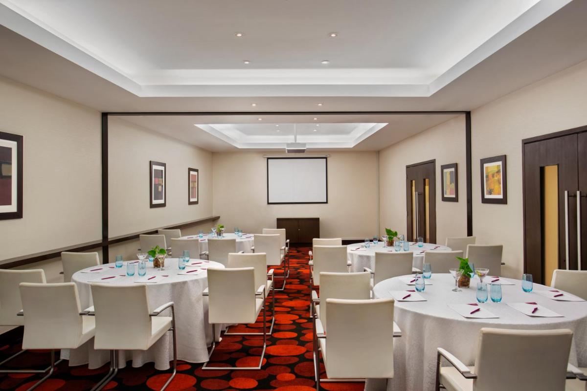 a conference room with white tables and chairs and a screen at The Oterra in Bengaluru +46 photos