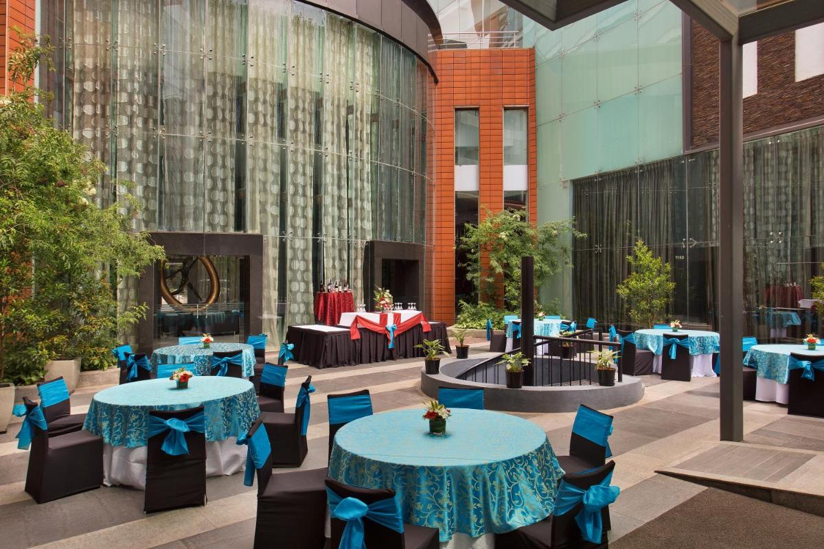 a courtyard with blue tables and chairs and a building at The Oterra in Bengaluru