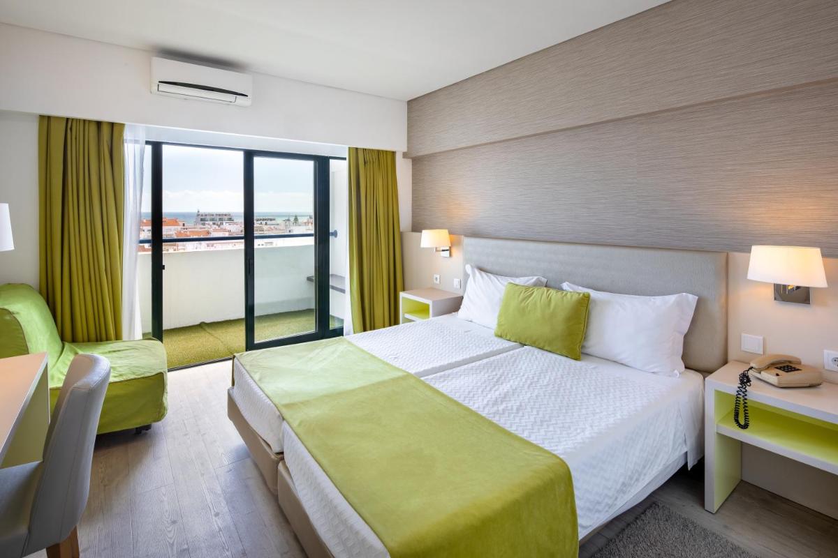 um quarto de hotel com uma cama grande e uma varanda em Hotel Navegadores em Monte Gordo