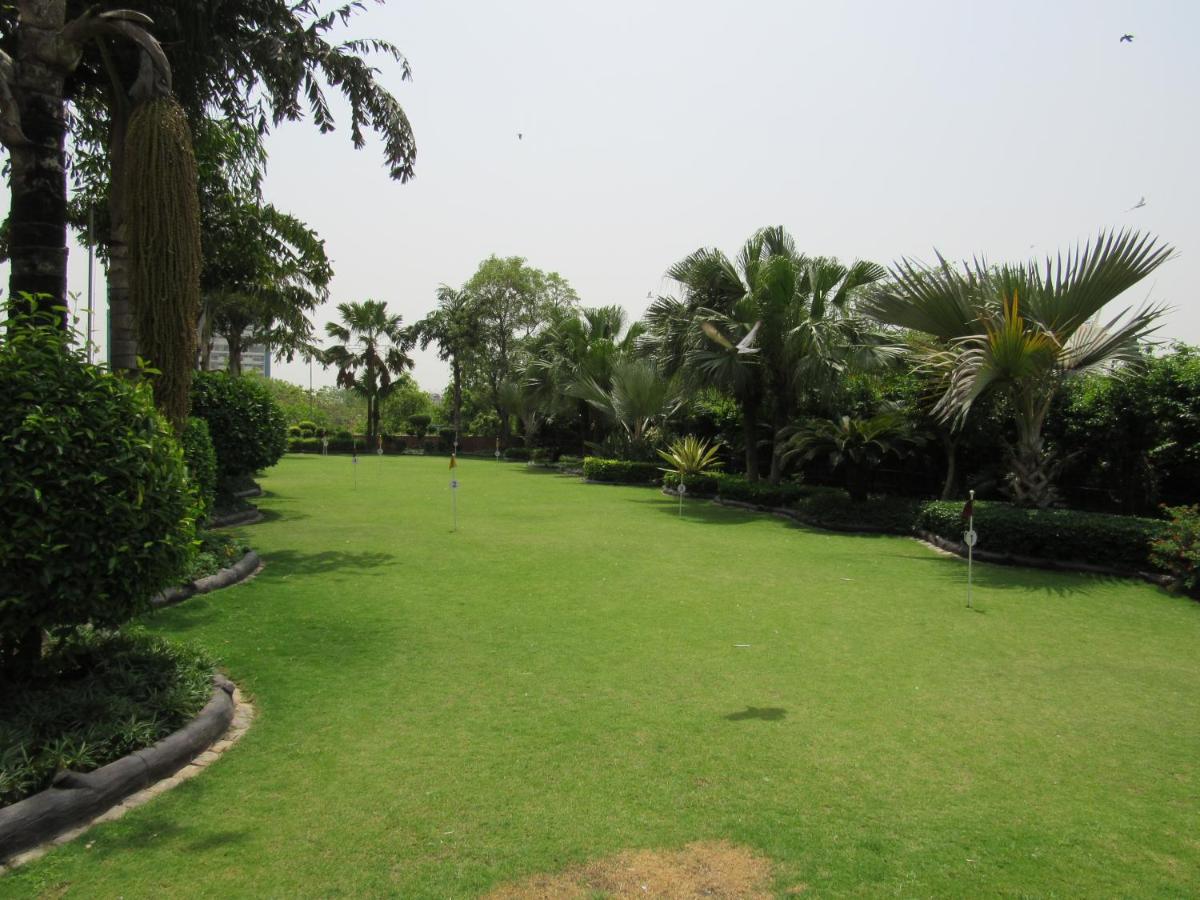 a large yard with green grass and palm trees at Eros Hotel New Delhi, Nehru Place in New Delhi a large yard with green grass and palm trees at Eros Hotel New Delhi, Nehru Place in New Delhi