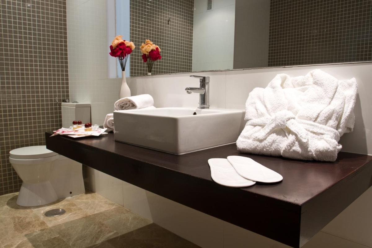 Un baño con lavabo y un inodoro con toallas. en Hotel & SPA Dynastic, en Benidorm