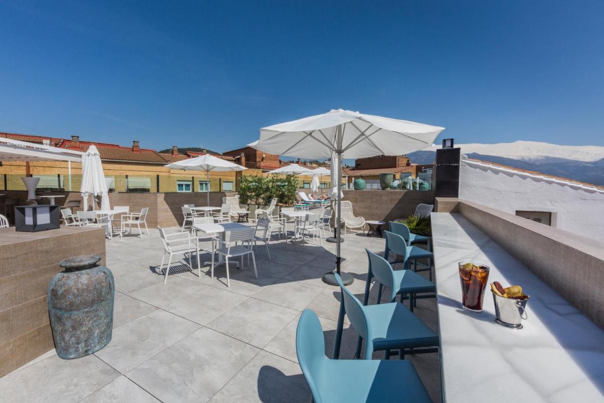 Un patio con sillas y mesas y una sombrilla. en Catalonia Granada, en Granada