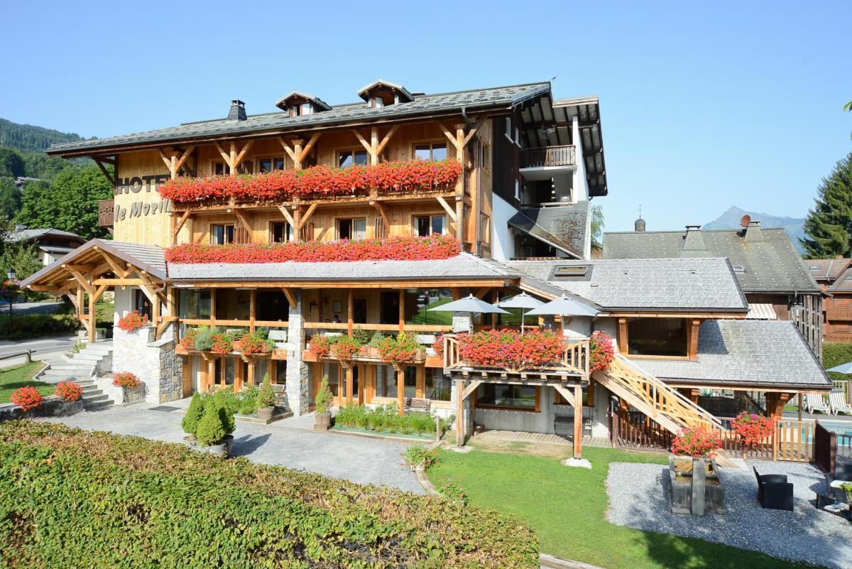 une grande maison avec des fleurs sur le devant dans l'établissement Café-Hôtel Le Morillon, Domaine du Grand Massif-Samoëns, à Morillon