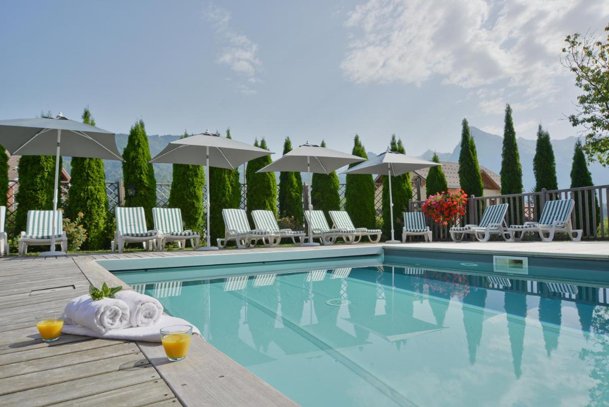 une piscine d'hôtel avec chaises longues et parasols dans l'établissement Café-Hôtel Le Morillon, Domaine du Grand Massif-Samoëns, à Morillon