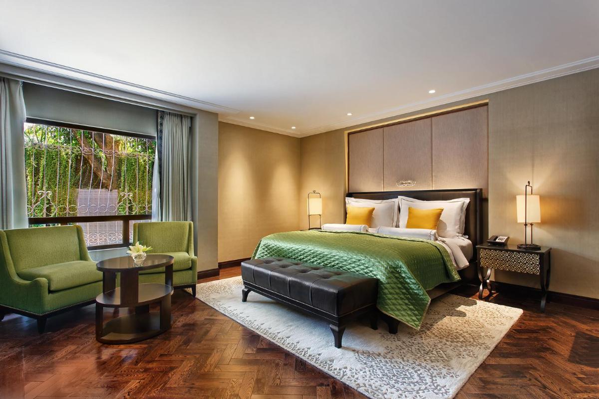 a bedroom with a green bed and two green chairs at The Claridges New Delhi in New Delhi a bedroom with a green bed and two green chairs at The Claridges New Delhi in New Delhi