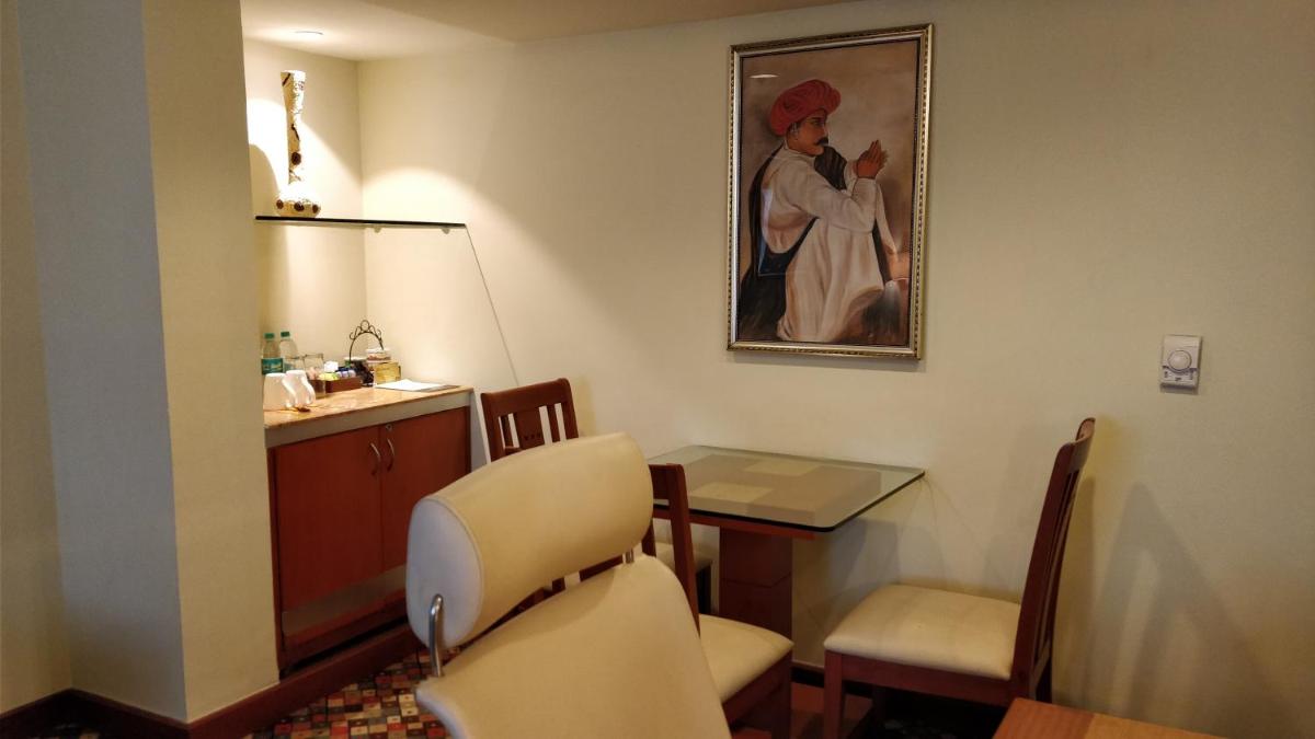 a waiting room with a table and a painting of a woman at The Suryaa New Delhi in New Delhi a waiting room with a table and a painting of a woman at The Suryaa New Delhi in New Delhi