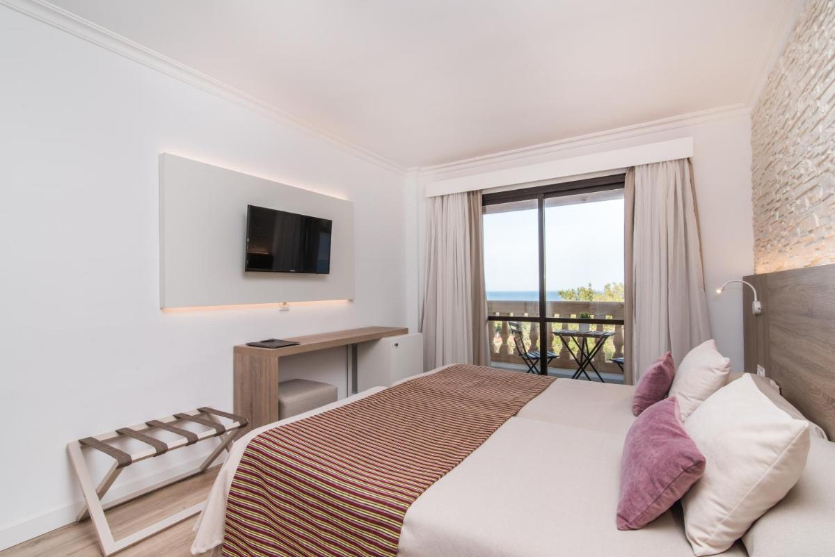 Un dormitorio con una cama y una ventana con vistas. en Hotel Na Taconera, en Cala Ratjada