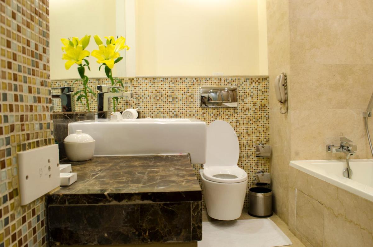a bathroom with a toilet and a sink and yellow flowers at Radisson Blu Hotel, Greater Noida in Greater Noida