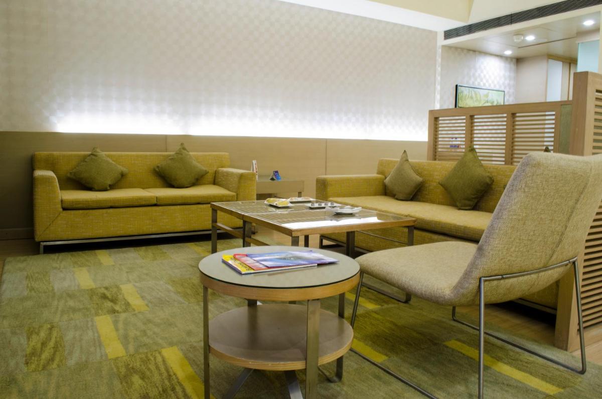 a living room with couches and a table and chairs at Radisson Blu Hotel, Greater Noida in Greater Noida