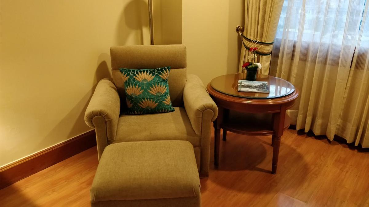 a living room with a chair and a table at Jaypee Vasant Continental in New Delhi