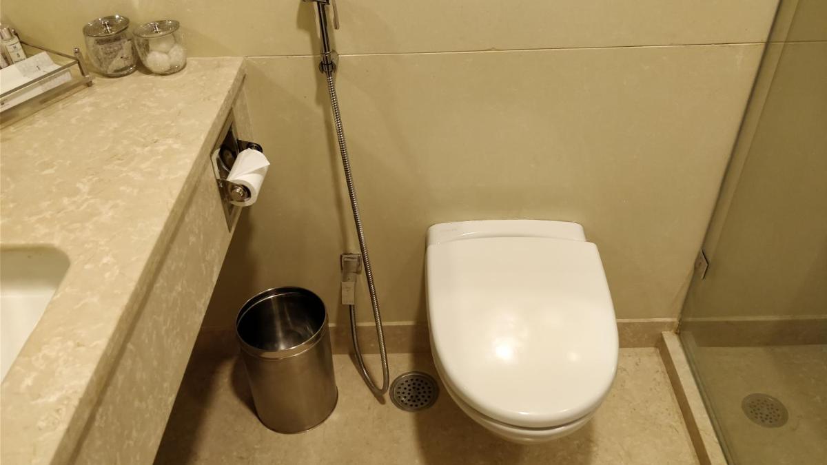 a bathroom with a white toilet and a sink at Jaypee Vasant Continental in New Delhi