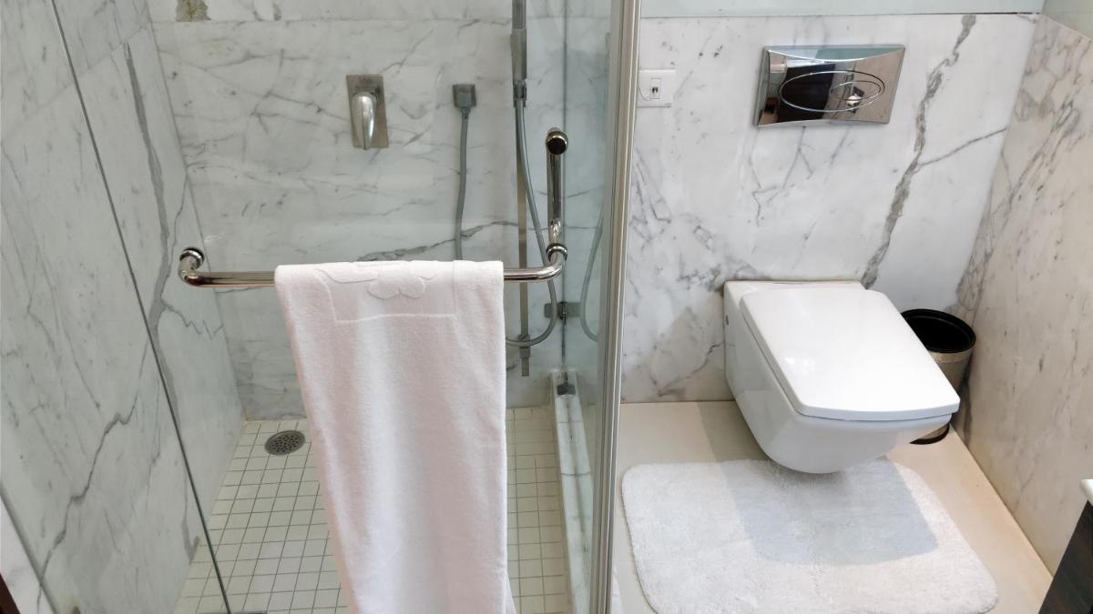 a bathroom with a toilet and a glass shower at Jaypee Vasant Continental in New Delhi