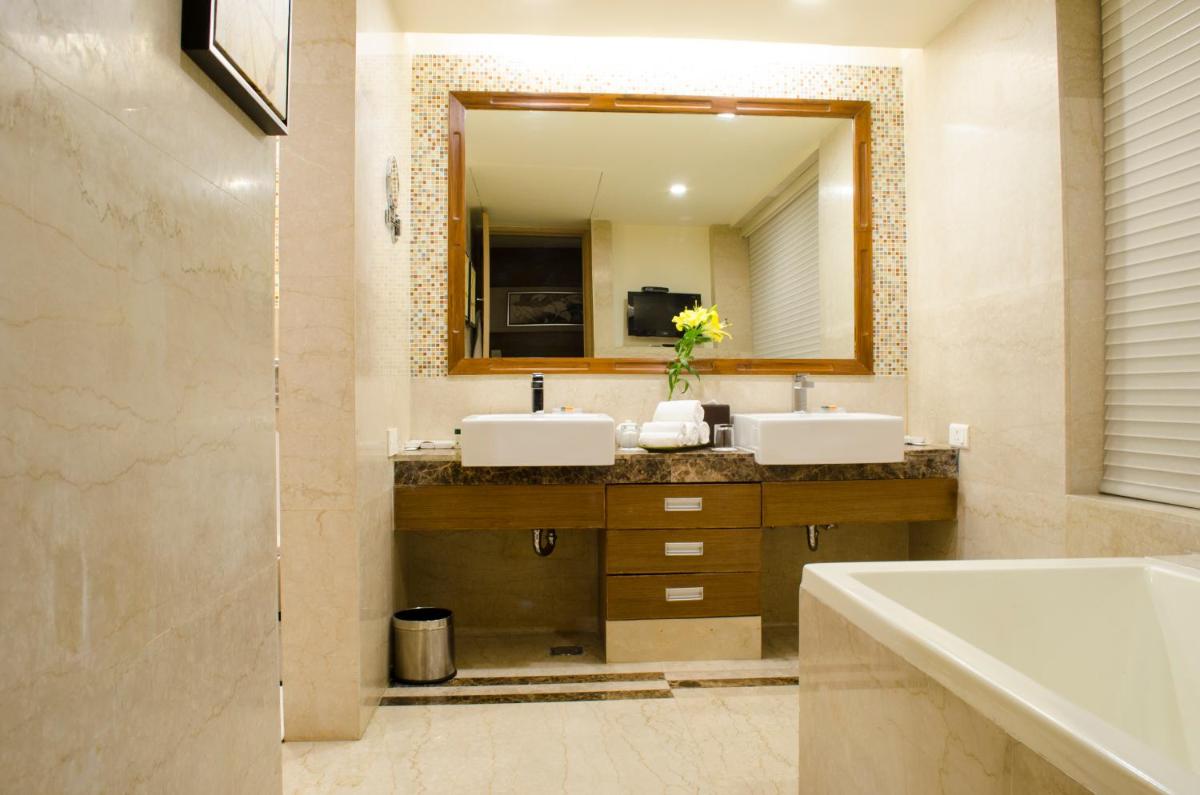 a bathroom with two sinks and a large mirror at Radisson Blu Hotel, Greater Noida in Greater Noida
