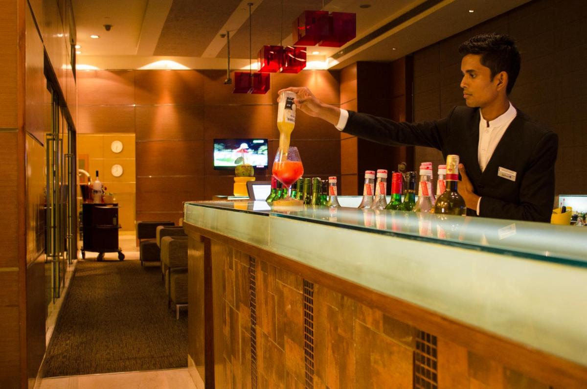 a man standing at a bar making a drink at Radisson Blu Hotel, Greater Noida in Greater Noida