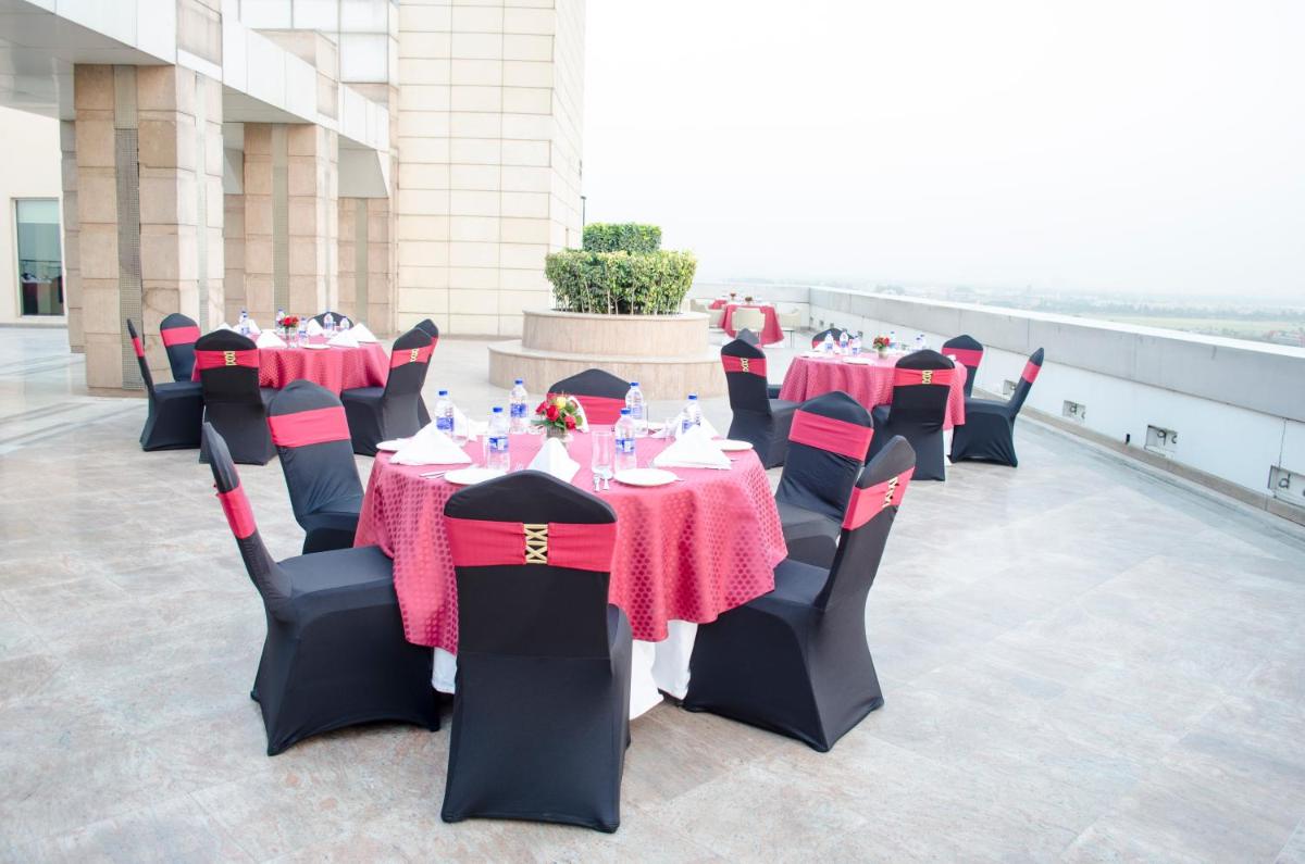 a row of tables and chairs with red and black table cloth at Radisson Blu Hotel, Greater Noida in Greater Noida