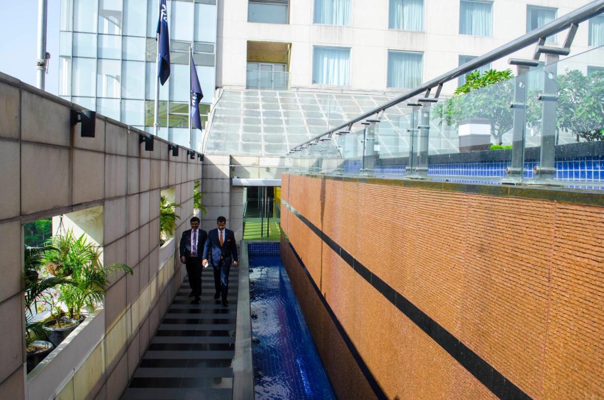 two men walking down stairs in a building at Radisson Blu Hotel, Greater Noida in Greater Noida