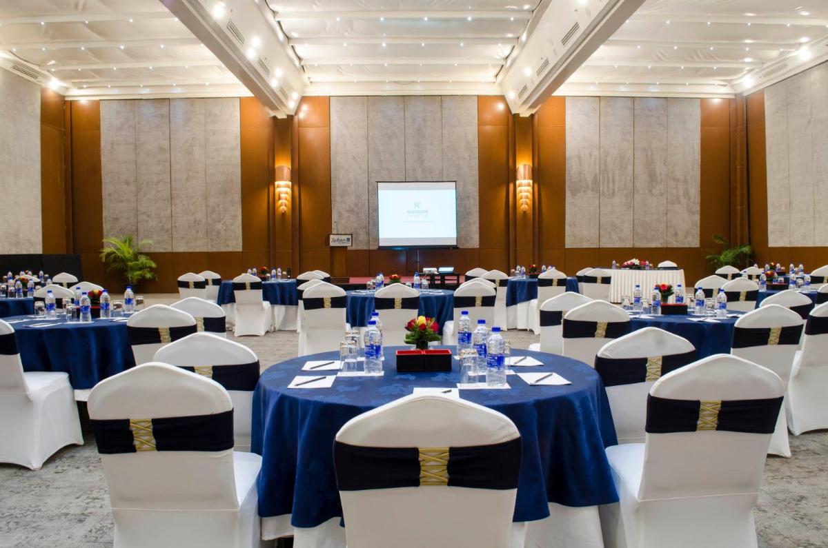 a conference room with tables and chairs and a screen at Radisson Blu Hotel, Greater Noida in Greater Noida