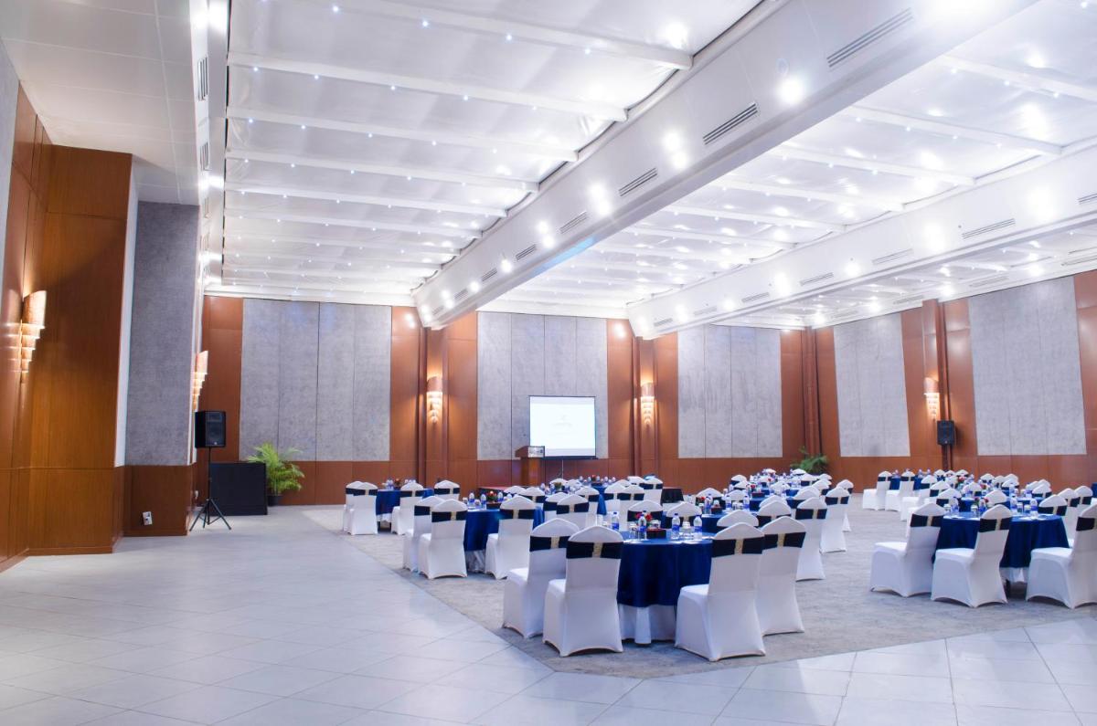 a large banquet hall with tables and chairs and a screen at Radisson Blu Hotel, Greater Noida in Greater Noida