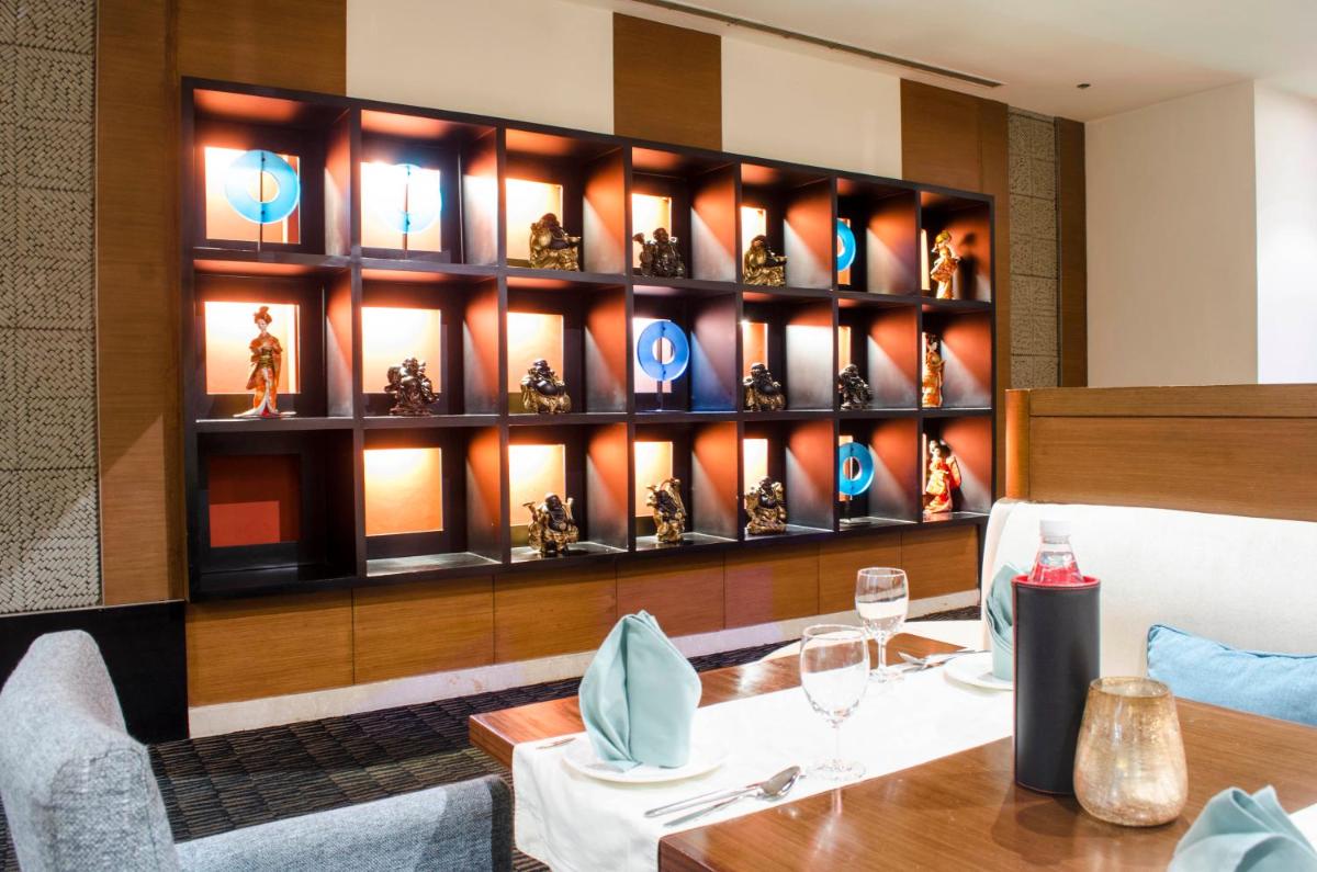 a dining room with a table and a shelf of trophies at Radisson Blu Hotel, Greater Noida in Greater Noida