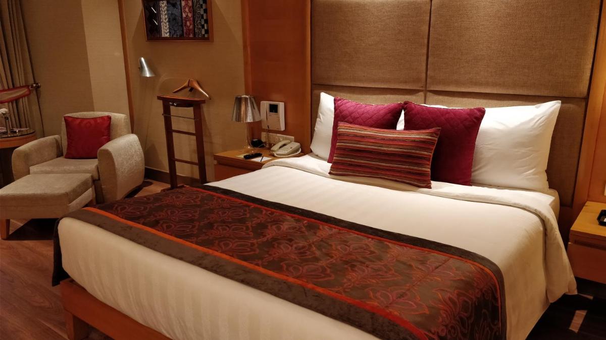 a hotel room with a large bed and a chair at Jaypee Vasant Continental in New Delhi