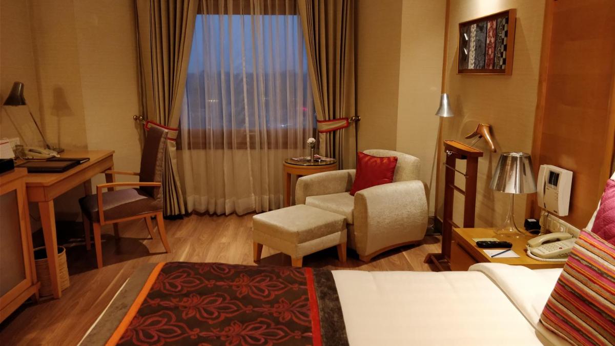 a hotel room with a bed and a chair and a desk at Jaypee Vasant Continental in New Delhi