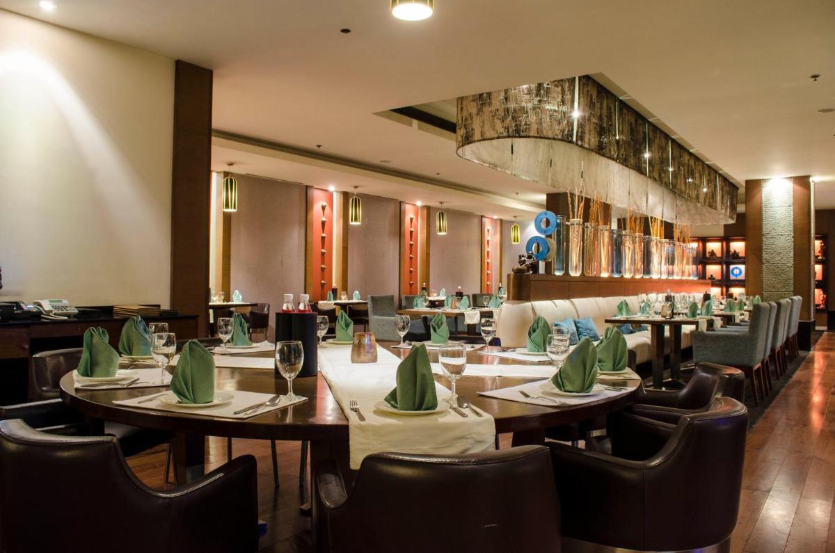 a restaurant with tables and chairs and a chandelier at Radisson Blu Hotel, Greater Noida in Greater Noida