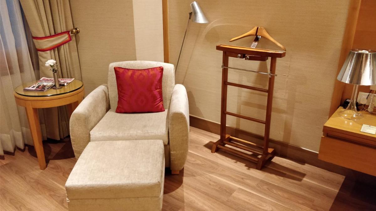 a living room with a chair and a red pillow at Jaypee Vasant Continental in New Delhi