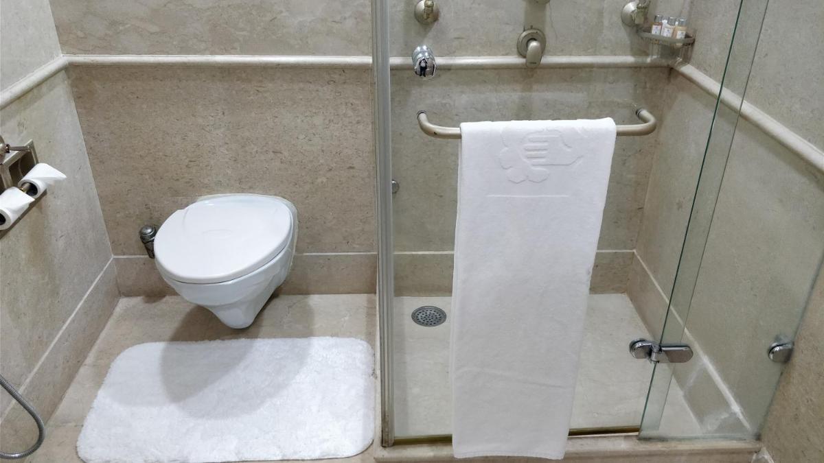 a bathroom with a toilet and a glass shower stall at Jaypee Vasant Continental in New Delhi