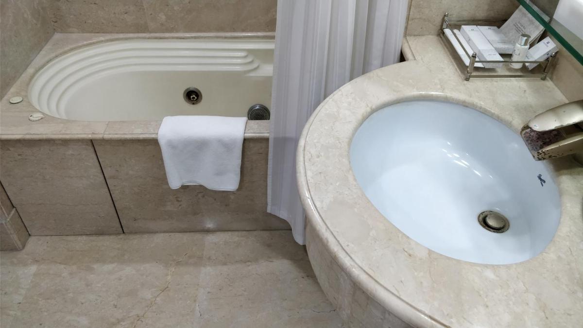 a bathroom with a sink and a bath tub at Jaypee Vasant Continental in New Delhi
