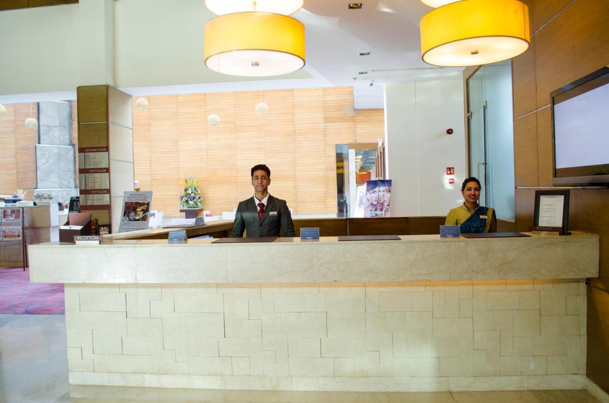 two people sitting at a counter in a lobby at Radisson Blu Hotel, Greater Noida in Greater Noida